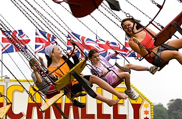 Findon village Sheep Fair Four children in motion riding on a swing carousel, United Kingdom