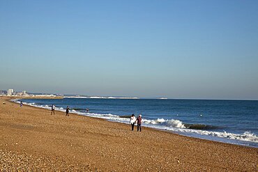 England, West Sussex, Shoreham-by-Sea, people walking along the waters edge on Shoreham beach