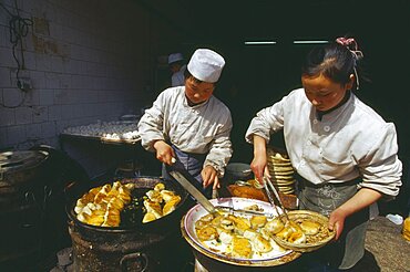 CHINA Shaanxi Province Xian Two cooks preparing dish of fried food.