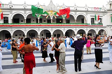 Couples dancing in the Zocalo with facade of government buildings behind hung with bright decorations in the national colours for Independence Day celebrations, Veracruz, Veracruz, Mexico