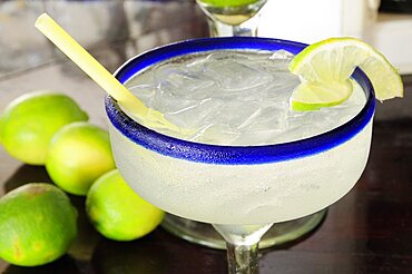 Frosted glass of a margarita cocktail served with ice and slice of lime with whole limes at side, Puerto Vallarta, Jalisco, Mexico