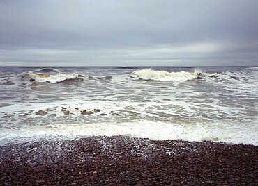 North facing shingle beach looking out across rough sea and surf, Kingston, Moray, Scotland