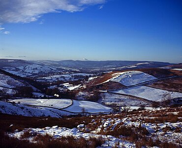 View westwards over snow covered moorland landscape and fields towards Peak District village from Higgartor, Hathersage, Derbyshire, England