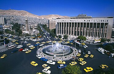 SYRIA South Damascus View over Tajrida Al Maghribiya Square with traffic encircling a central fountain.  Modern facade of the Central Bank top right.