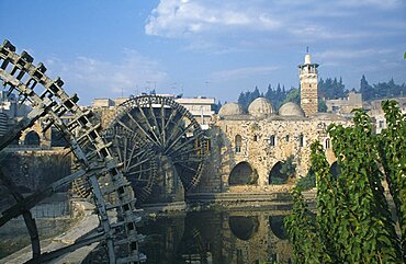 SYRIA Central Hama Wooden norias or waterwheels on the Orontes river and the Al-Nuri Mosque dating from 1172 and built of limestone and basalt.