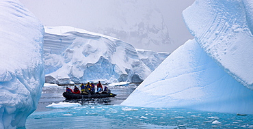 Eco tourists cruise around an Iceberg graveyard in Zodiac boats, Hidden Bay, Antarctica, Polar Regions