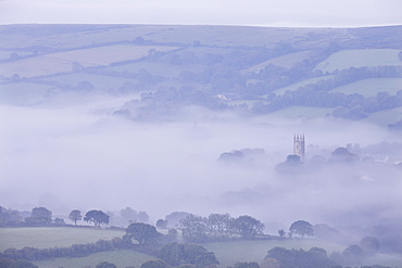 Morning mist swirls around the church tower of Widecombe in the Moor village on Dartmoor, Devon, England, United Kingdom, Europe