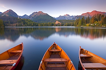 Rowing boats and mountains beneath a twilight sky in autumn, Strbske Pleso Lake in the High Tatras, Slovakia, Europe