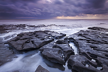 Waves rush around eroded rock ledges at Southerndown on the Glamorgan Heritage Coast, Wales, United Kingdom, Europe