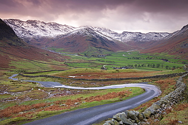 Small winding road leading into the Langdale Valley, surrounded by snow clad mountains, Lake District National Park, Cumbria, England, United Kingdom, Europe