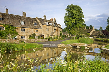 Cottages and footbridge over the River Eye in the Cotswolds village of Lower Slaughter, Gloucestershire, England, United Kingdom, Europe 