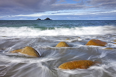 Waves swirl around rocks on Porth Nanven beach, Cornwall, England, United Kingdom, Europe 