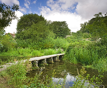 Clapper bridge crossing the River Leach in the pretty Cotswolds village of Eastleach Turville, Gloucestershire, England, United Kingdom, Europe 