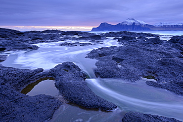 Atlantic waves surge over the black basalt ledges at Gjogv on the island of Eysturoy, Faroe Islands, Denmark, Europe