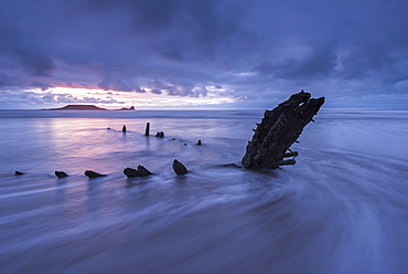 Shipwreck of the Helvetia on Rhossili Beach, looking towards Worms Head at sunset, Rhossili, Gower, Wales, United Kingdom, Europe