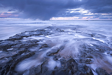 A winter storm passes over the Farne Islands, photographed from the basalt shore near Bamburgh Beach, Northumberland, England, United Kingdom, Europe