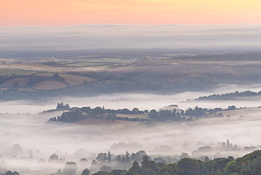 Mist floats over rolling countryside below Castle Drogo at dawn, Dartmoor, Devon, England, United Kingdom, Europe