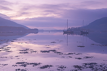 Yachts moored on a mirror still Loch Leven at twilight, Glencoe, Highland, Scotland, United Kingdom, Europe