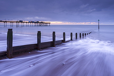 Waves wash against the wooden groynes near Teignmouth Pier at sunrise, Devon, England, United Kingdom, Europe