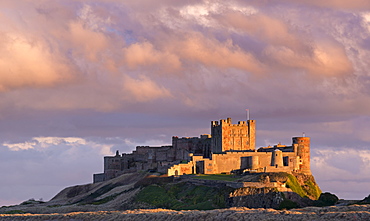 Rich evening sunlight glows against Bamburgh Castle at sunset, Northumberland, England, United Kingdom, Europe