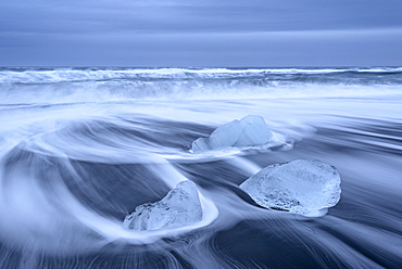 Waves wash ice onto the black sand beach at Jokulsarlon, Iceland, Polar Regions