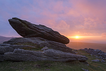 Colourful sunset over a granite logan stone on Belstone Tor, Dartmoor, Devon, England, United Kingdom, Europe