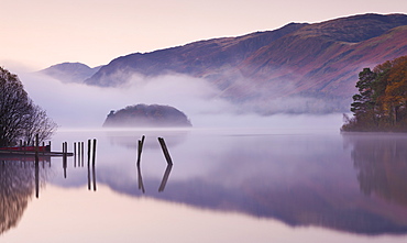 Mist surrounds a peaceful Derwent Water at dawn in autumn, Lake District National Park, Cumbria, England, United Kingdom, Europe