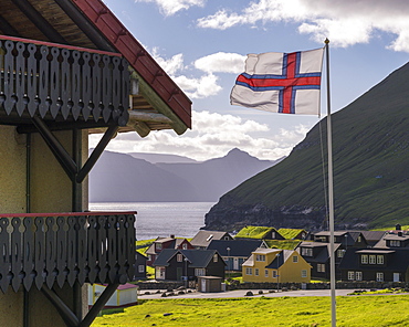 Faroese flag flying in the breeze above the village of Gjogv in the Faroe Islands, Denmark, Europe