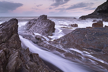 Waves surge around the jagged rocks on Wildersmouth Beach, Ilfracombe, Devon, England, United Kingdom, Europe