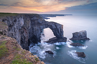 Colourful dawn sky above the Green Bridge of Wales natural arch in Pembrokeshire, Wales, United Kingdom, Europe