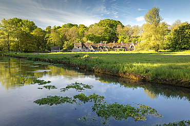 Arlington Row cottages across the River Coln in the Cotswolds village of Bibury, Gloucestershire, England, United Kingdom, Europe