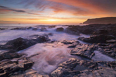 Colourful Cornish sunset above rocky ledges near Polzeath, Cornwall, England, United Kingdom, Europe