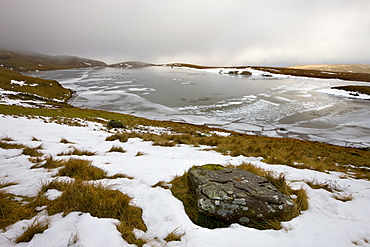 Melting snow on the moorland above an ice covered Llyn y Fan Fawr in winter, Black Mountain, Brecon Beacons National Park, Wales, United Kingdom, Europe