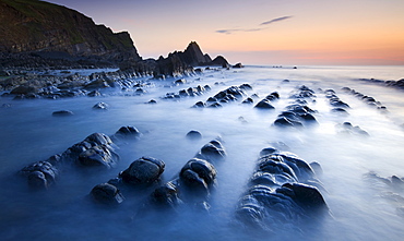 High tide gradually submerges the rocky shores of Blegberry Bay at sunset, Hartland, Devon, England, United Kingdom, Europe