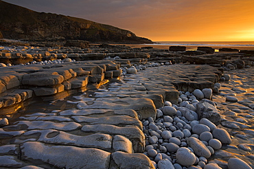 Rock ledges and pebbles in golden sunset light, Dunraven Bay, Southerndown, Wales, United Kingdom, Europe