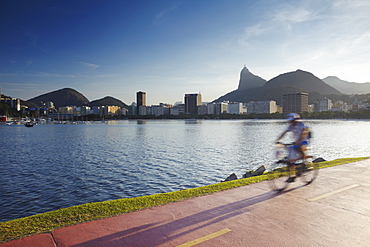 Cyclist on pathway around Botafogo Bay with Christ the Redeemer statue (Cristo Redentor) in the background, Rio de Janeiro, Brazil, South America 