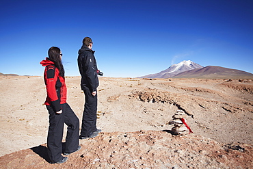 Couple looking at volcano on Altiplano, Potosi Department, Bolivia, South America