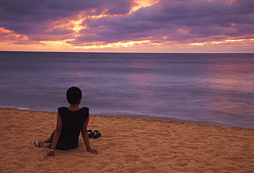 Woman sitting on beach at sunset, Negombo, Sri Lanka, Asia