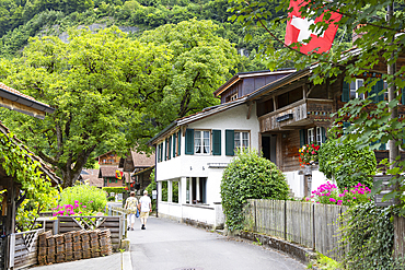 Couple walking past traditional chalets, Iseltwald, Switzerland