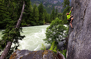 A climber scales riverside cliffs above the Green River, Whistler, British Columbia, Canada, North America