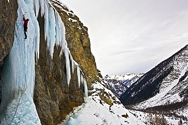 An ice climber ascending a frozen cascade in the Fournel Valley, Ecrins Massif, France, Europe