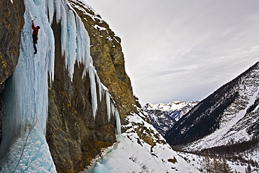 An ice climber ascending a frozen cascade in the Fournel Valley, Ecrins Massif, France, Europe