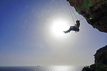 Rock climber lowering off after ascending a steep climb on the cliffs of Malta, Mediterranean, Europe