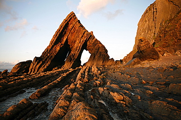 The light of the setting sun illuminates the unusual architecture of Blackchurch Rock, which lies under cliffs between Clovelly and Hartland Point, Culm Coast, North Devon, England, United Kingdom, Europe