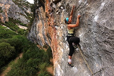 Climber makes her way up one of the rock faces of the celebrated Mascun Gorge, Sierra de Guara mountains, Aragon, Spain