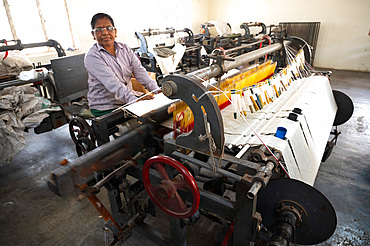 Woman at large loom weaving spun cotton into Khadi fabric in the Gandhi Khadi Plaza