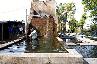 Man rinsing fabric of excess dye in factory well after block printing, before leaving in the sun to dry.