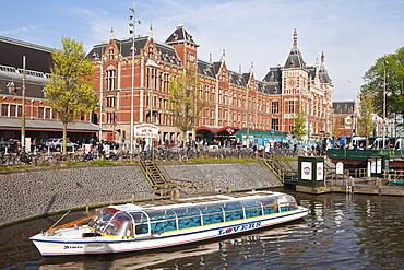 Canal tour boat outside Centraal Station, the central train station, Amsterdam, Netherlands, Europe