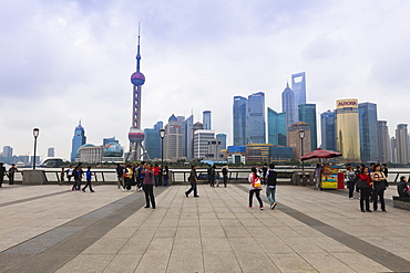 Pedestrians and tourists on the Bund, the futuristic skyline of Pudong across the Huangpu River beyond, Shanghai, China, Asia