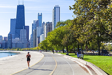 Jogger on North Avenue Beach with John Hancock Center and city skyline behind, Chicago, Illinois, United States of America, North America